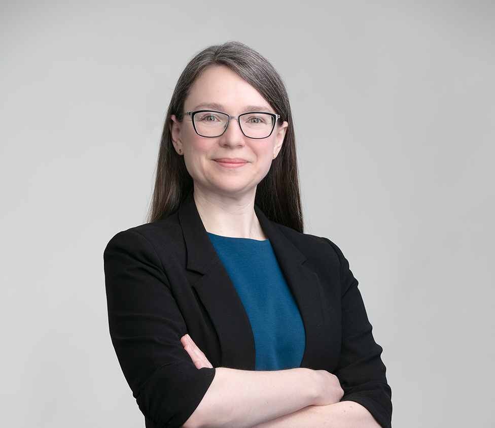 Laura Boudreau headshot - she is wearing a black blazer and dark blue top. Standing with her arms crossed.
